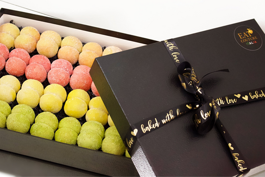 Box of colorful peach cookies with a decorative ribbon on a white background